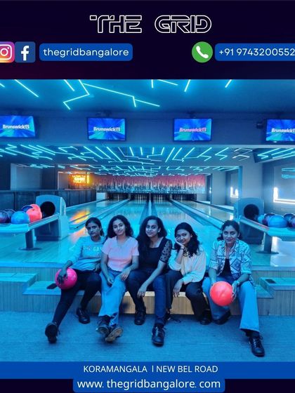 A group of girls posing with bowling balls on our neon-green lit lanes.