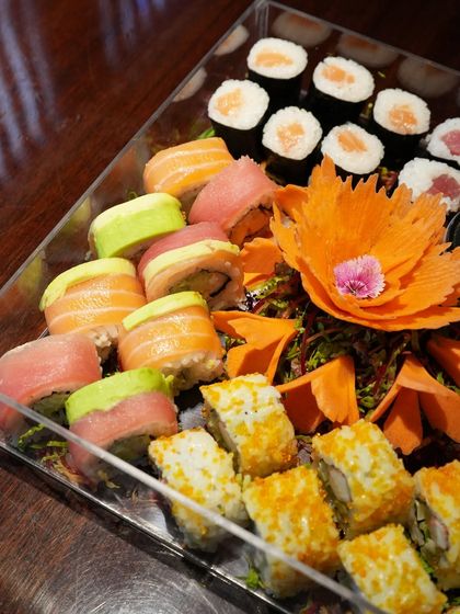 This custom platter combines different styles of sushi, from classic salmon and tuna maki to colorful rainbow rolls and crunchy tobiko-coated rolls. The carved vegetable garnish adds a touch of artistry.