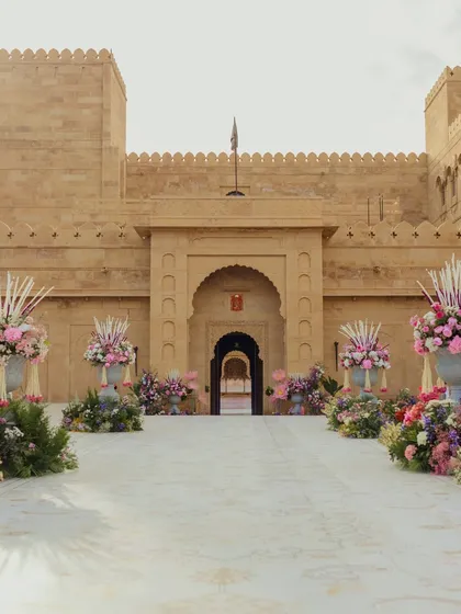 The grand entrance to the wedding at Suryagarh, with the palace's majestic architecture complemented by large, elegant floral arrangements lining the path.