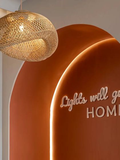 A close-up of the dining nook's accent wall, featuring the custom neon sign and a beautiful woven pendant light that adds to the warm, organic feel.