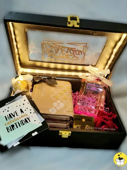 A premium birthday hamper in a black box with gold accents, containing a diary, chocolates, and other custom items.
