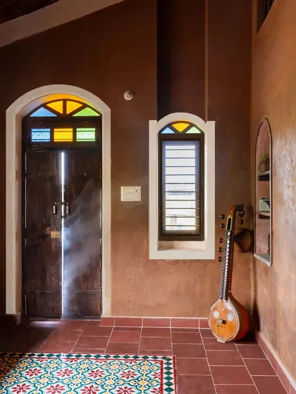 Simplicity is at the core of our design philosophy. In this corner of the Doddaballapura mud house, the earthy mud plaster walls, reclaimed wooden door with colored glass, and patterned tile floor come together to create a space that is both humble and full of character.