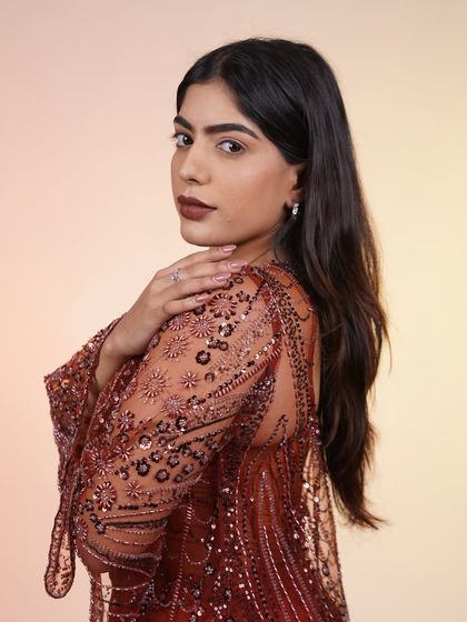 A close-up of our rust-colored Indo-Western outfit. The intricate beadwork and bell sleeves make it a perfect choice for a sangeet or cocktail party.