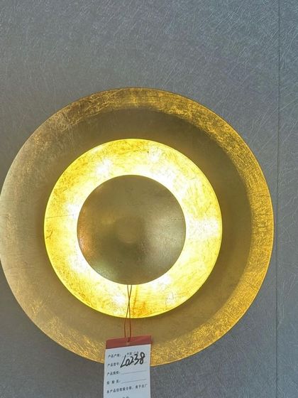 The gold-leaf wall sconce when illuminated. The textured surface catches the light beautifully, making it a stunning focal point.