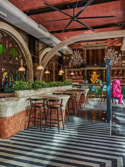 The bar area at Suzy Q, with its striking black-and-white striped floor and large, arched stained-glass windows. The design is a testament to our love for creating iconic, memorable spaces.