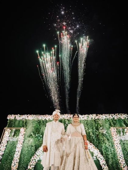 A spectacular end to the wedding ceremony. As the couple stood for their first portrait as husband and wife, a display of fireworks lit up the night sky behind them, creating a truly cinematic and celebratory moment.