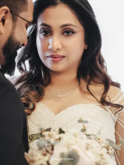 A powerful and intimate portrait of the bride looking directly at the camera, her groom's face partially in the frame.