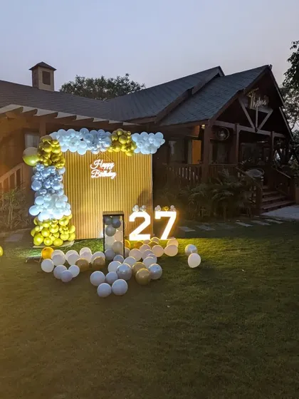 A wide shot of the outdoor 27th birthday setup at dusk, showing how the illuminated decor stands out against the evening sky.