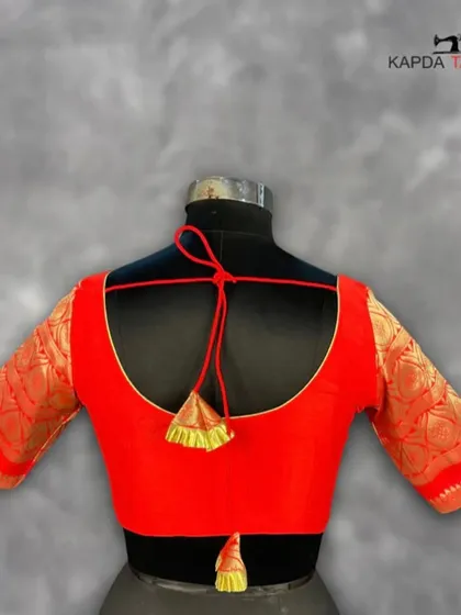 This deep red brocade blouse is a statement of elegance. The rich texture of the fabric and the classic U-back with a dori tie make it a sophisticated choice for any wedding or festive event.