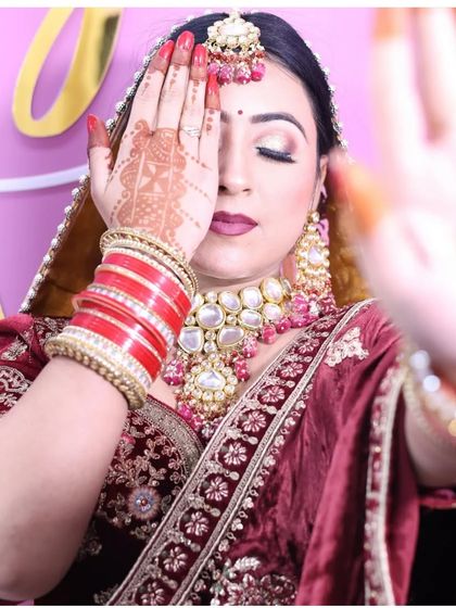 An artistic bridal shot focusing on the henna design and the beautiful contrast between the red chooda and the maroon lehenga. The oversized Kundan jewellery adds a touch of grandeur.