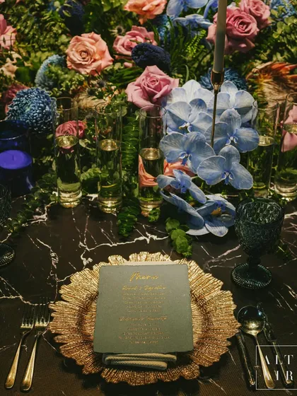 A tablescape is a story in miniature. For this 'Midnight Mirage' sangeet, I layered rich cobalt and blue tones with lush florals and soft gold accents, creating a setting where every detail, from the custom menu to the charger plates, contributes to an atmosphere of mystic glamour.