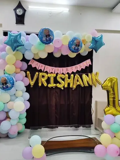 A Boss Baby themed first birthday decoration for a home setting, with a pastel balloon arch and a personalized name banner.