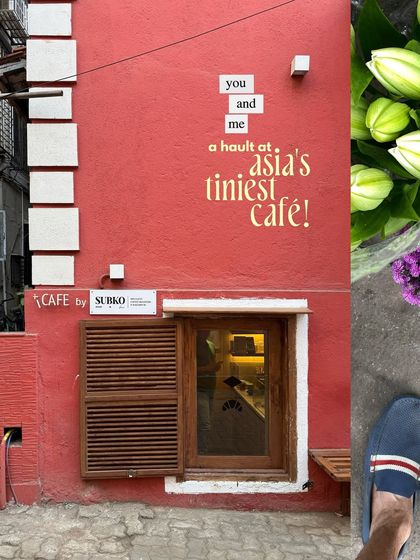 The vibrant red facade of Subko Mini, Asia's tiniest cafe, with its charming wooden window shutter.