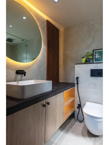 After: This sleek, modern bathroom is a world away from its previous state. We used large-format tiles, a backlit mirror, and wood-look cabinets to create a spa-like feel. Swipe to see the before.