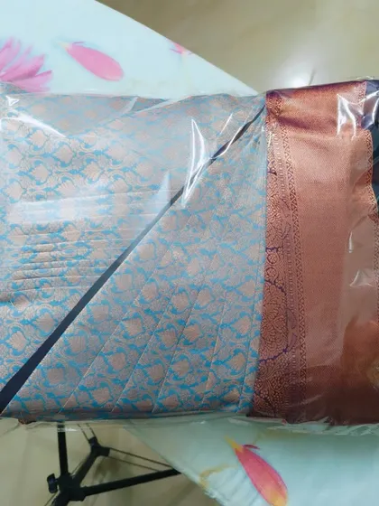 A light blue saree, pre-pleated and packed. I can work with a wide variety of saree fabrics, from heavy silks to lighter materials.