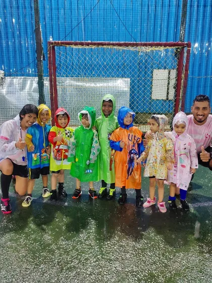 Our toddlers in their colorful raincoats, ready for a fun football session in the rain with their coaches.