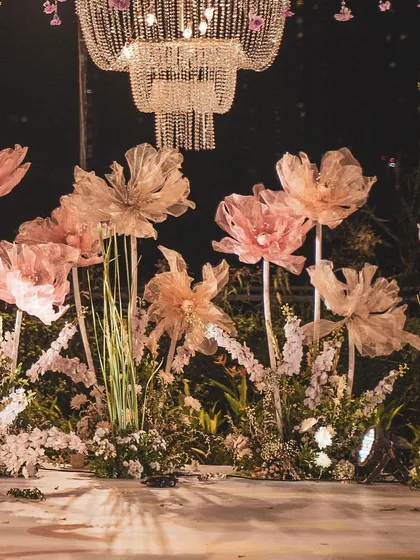 A full view of the stage adorned with glowing, oversized paper flowers. This creative and artistic approach to floral decor makes for a truly unique and memorable wedding design.