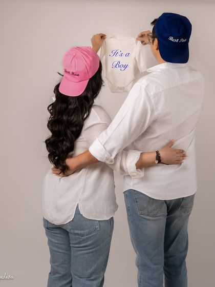 A fun and cute gender reveal. The "Best Mom" and "Best Dad" hats with the "It's a Boy" onesie are a sweet and personal touch for a casual shoot.
