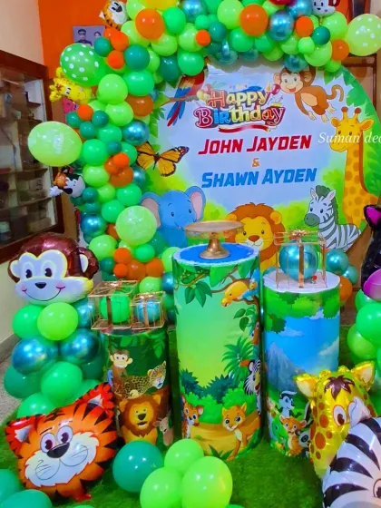Another angle of the vibrant jungle party setup, highlighting the lush green artificial grass mat and the colorful balloon arch that frames the main display area.