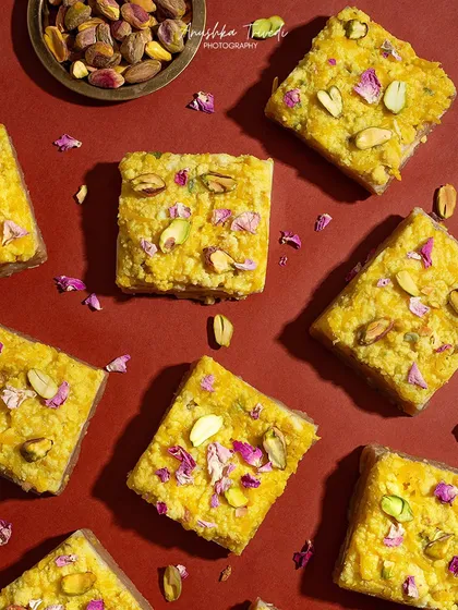 A flatlay of festive Indian sweets on a vibrant red background. This kind of shot is perfect for showcasing a variety of mithai in a modern, graphic way.