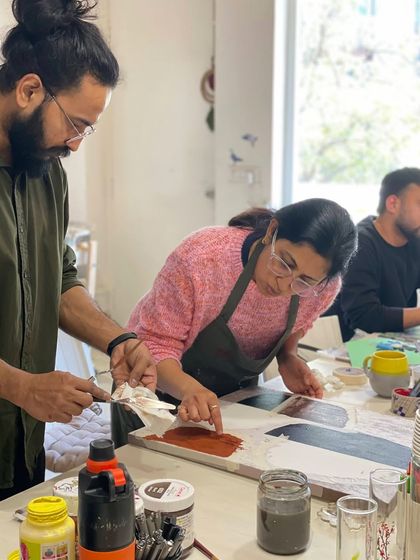 A mentor helps a participant with texture painting, demonstrating a technique with a palette knife. Our mentors are practicing artists passionate about sharing their skills.