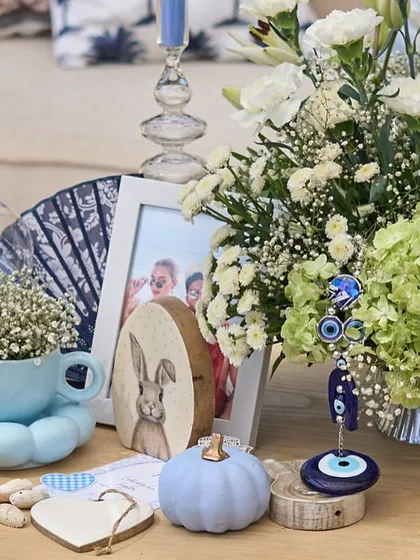 A close-up of the tablescape, showing the variety of textures and objects used, from ceramic pumpkins to seashells and an evil eye charm.