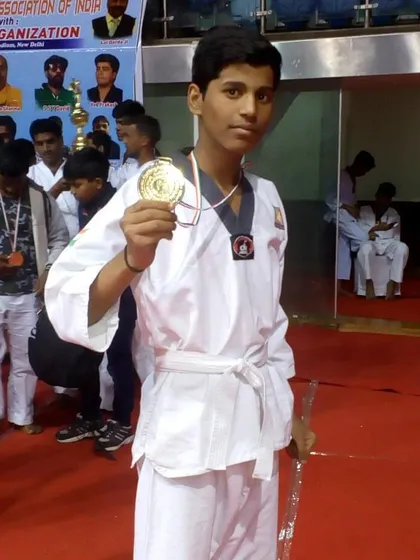 A young student proudly displays his gold medal after winning his category at the national championship.