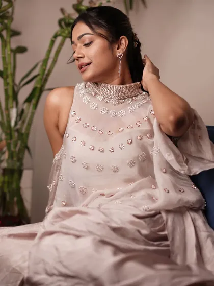 The delicate pearl and sequin work on the sheer cape of this outfit adds a touch of sophistication. It's a subtle detail that makes the look special and suitable for media events.
