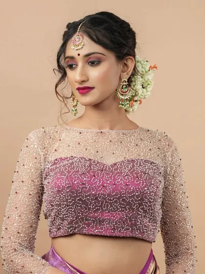 For moments that require extra sparkle, this party-wear blouse is a favorite. It features a delicate sweetheart neckline overlaid with a sheer, boat-neck layer, all meticulously hand-embroidered with beads. The full-length sheer sleeves add a touch of sophisticated glamour.