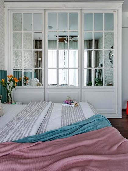 A wider view of the 'Urban Oasis' bedroom, showing the interplay of textures. The white brick wall, the mirrored wardrobe, and the colorful textiles on the bed create a vibrant yet harmonious space.