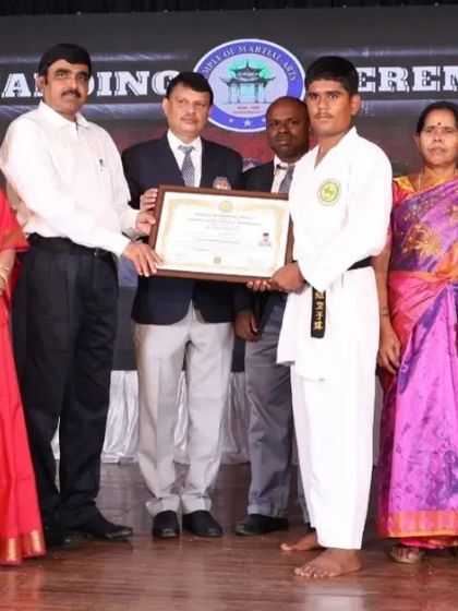 We are a karate family. A student stands proudly with his parents and instructors during the black belt awarding ceremony.
