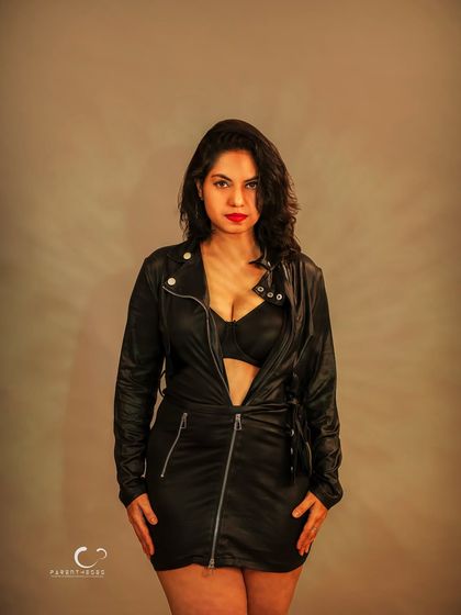 A powerful, direct-to-camera portrait. The stark lighting and simple background ensure all focus is on her intense gaze and unapologetic presence.