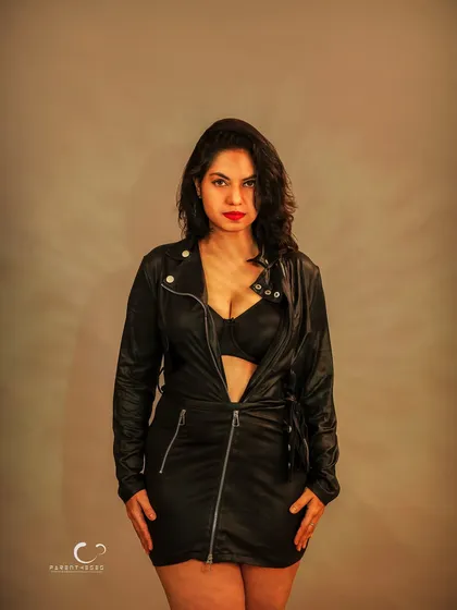 A powerful, direct-to-camera portrait. The stark lighting and simple background ensure all focus is on her intense gaze and unapologetic presence.
