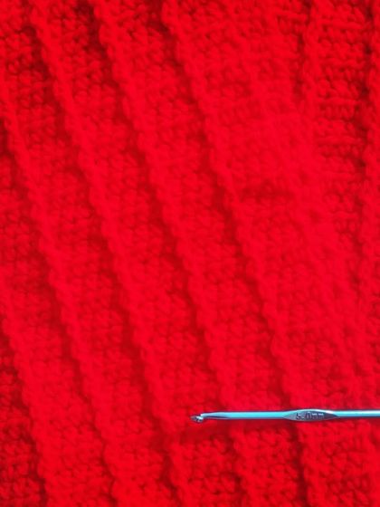 A close-up of the rich red crochet fabric. The simple stitches create such a lovely and classic design.