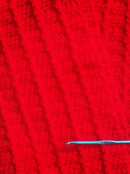 A close-up of the rich red crochet fabric. The simple stitches create such a lovely and classic design.