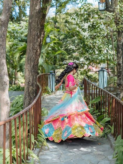 A shot of the bride walking along a rustic pathway, her colorful lehenga creating a beautiful contrast with the greenery.