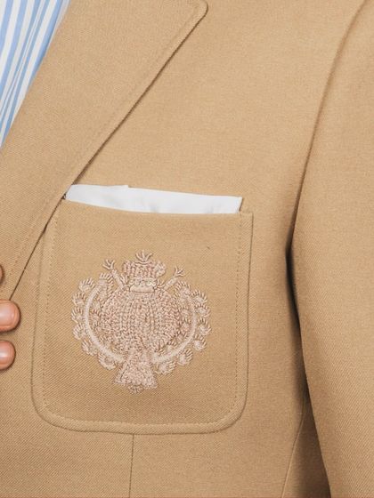 A detailed shot of the embroidered pocket on the tan suit. I offer custom monograms and crests to make your garment truly one of a kind.