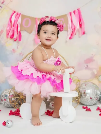A sweet first birthday girl on her little white tricycle, surrounded by disco balls for a touch of sparkle.