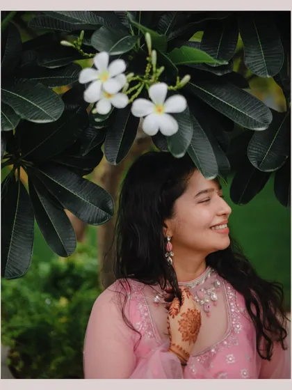 A beautiful, happy portrait of the bride from the Roka ceremony, her smile framed by lovely white flowers.