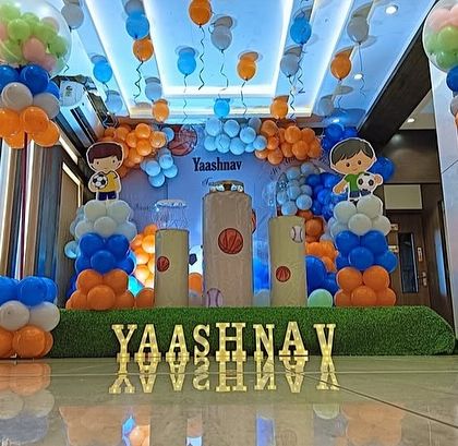 A wider view of the sports-themed birthday stage, showing the ceiling decoration with hanging balloons.