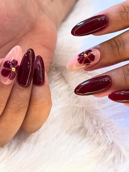 A closer look at this rich and elegant floral manicure. The deep maroon flowers with gold centers create a sophisticated contrast against the sheer pink accent nails.