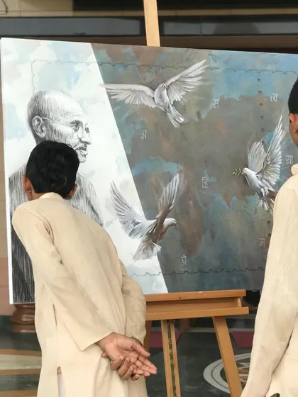 Young students at the camp observing the finished painting of Gandhiji, which depicts his message of peace.