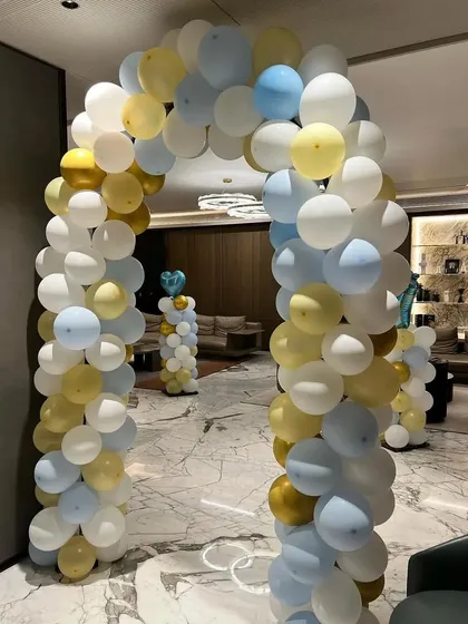 A simple balloon archway in white, yellow, and light blue to welcome guests to the baby shower.