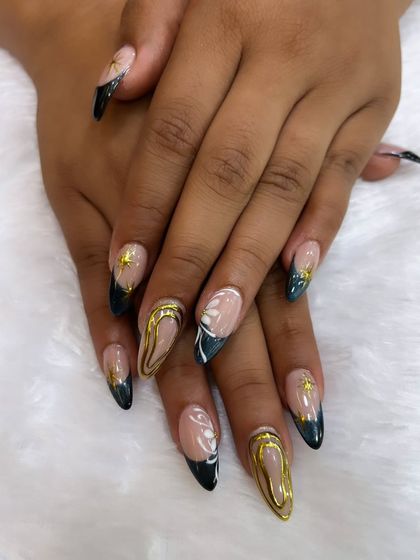 A close-up of our detailed artistic work. This set features stiletto nails with a dark teal French tip, raised gold chrome, and delicate white and gold accents.