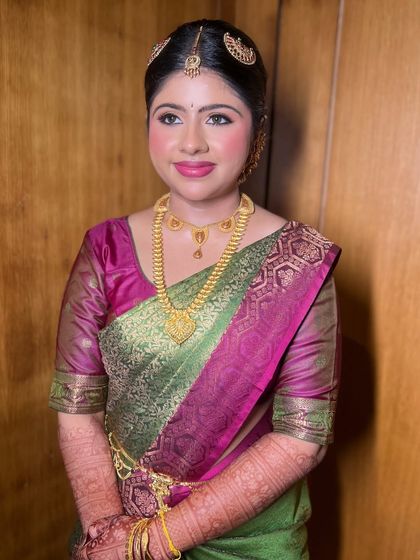 A smiling portrait of Mayuri. The makeup enhances her features beautifully, complementing her colorful Kanjeevaram saree.