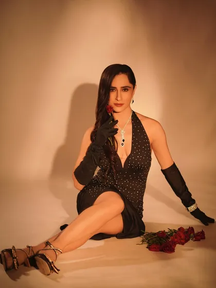 A full view of the glamorous look, showing the elegant seated pose and the scattered roses. This shot captures the complete styling, from the hair and makeup to the footwear.
