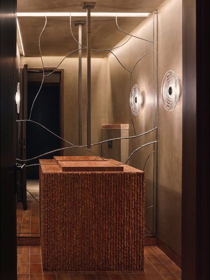 This powder room features a highly textured, custom-designed vanity that feels like a monolithic sculpture. The organic metalwork on the wall adds an artistic, linear contrast to the space.