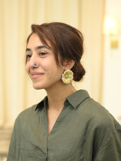 A client trying on a pair of floral studs, her friend looking on. Shopping for jewelry can be a wonderful shared experience.
