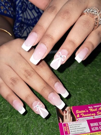 A classic French manicure on long square nails with a delicate, hand-painted white bow and a single rhinestone for a touch of simple elegance.