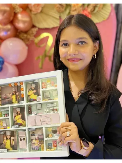 The talented young baker herself, proudly holding the frame that was custom-made to celebrate her passion and creativity.
